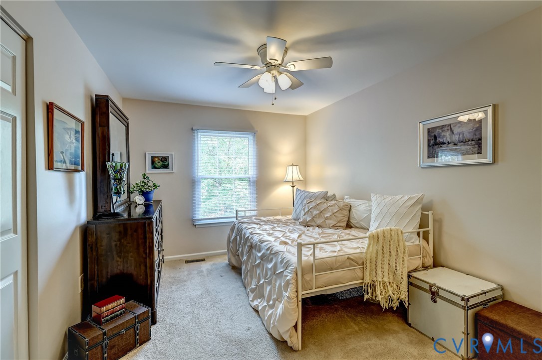 Furnished bedroom with a white daybed, dark wooden dresser, and window with blinds.