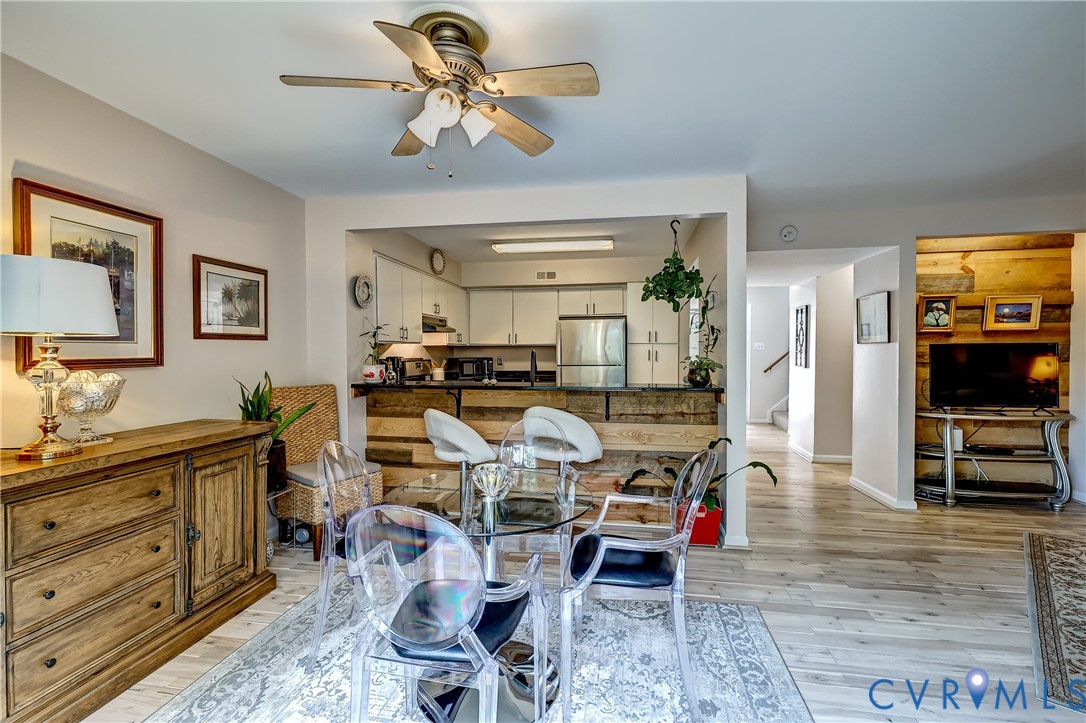 Open-plan dining room with a glass table and clear chairs beside a white kitchen.