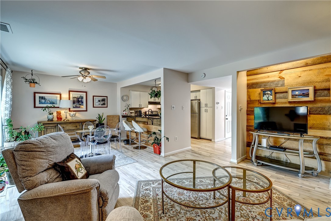 Open-plan living and dining room with a gray recliner and distinctive wood-paneled TV wall.