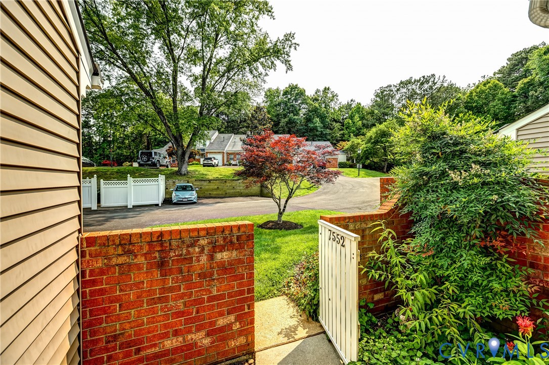 Gated brick entrance to 7552 Ingelnook Ct, with a landscaped path and mature trees.