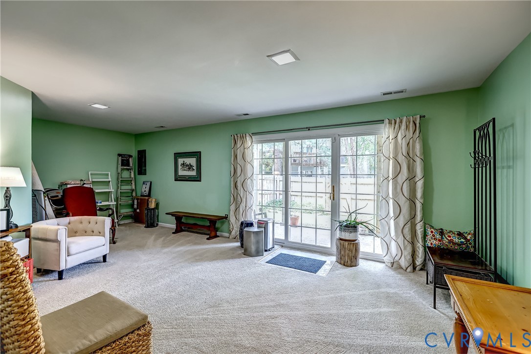 Carpeted living room with pale green walls and large sliding glass doors to a patio.