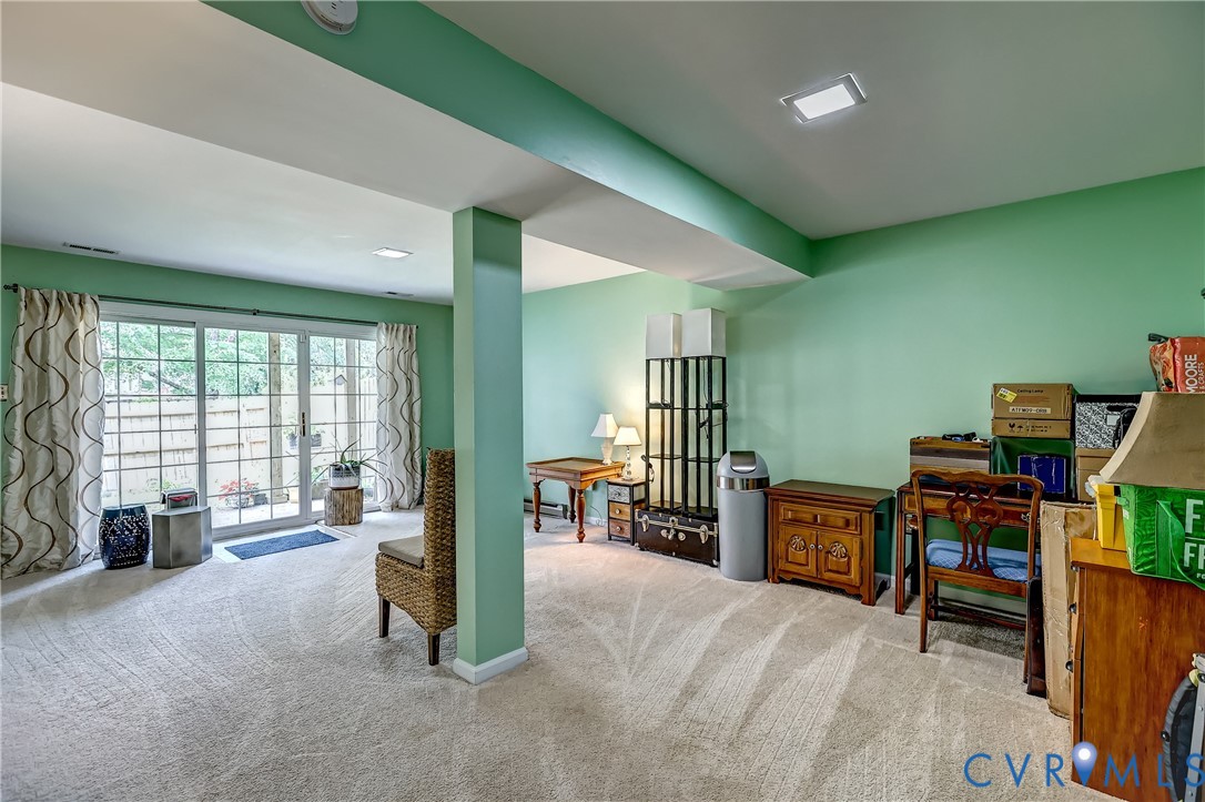 Furnished carpeted room with mint-green walls, a support column, and sliding glass doors.