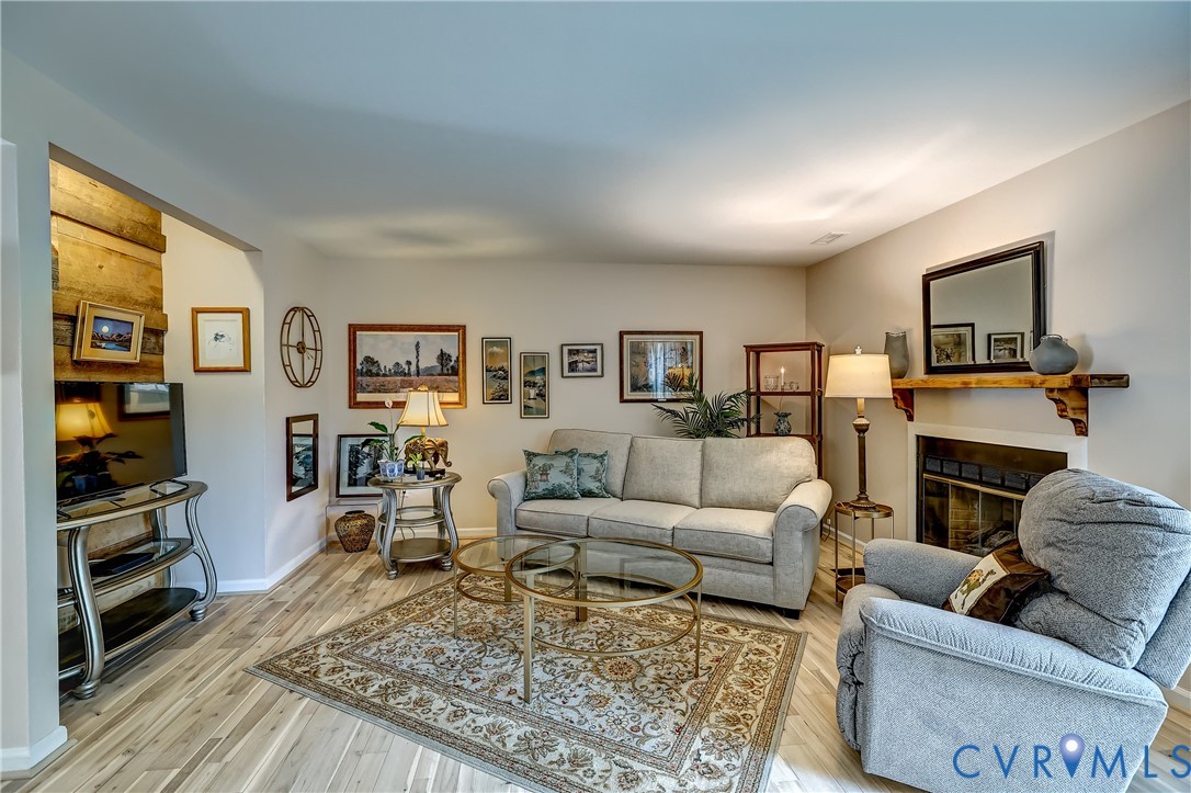 Living room with a fireplace, gray seating, framed art, and a patterned rug.