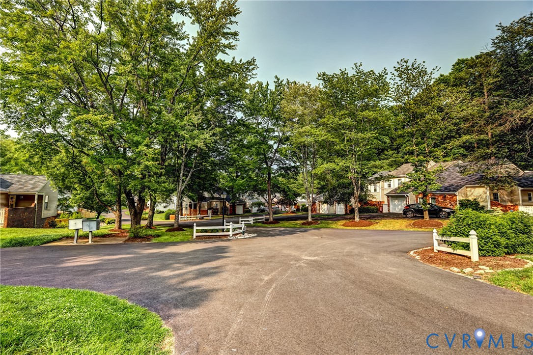 Tree-lined cul-de-sac with detached homes, lawns, and white fences.