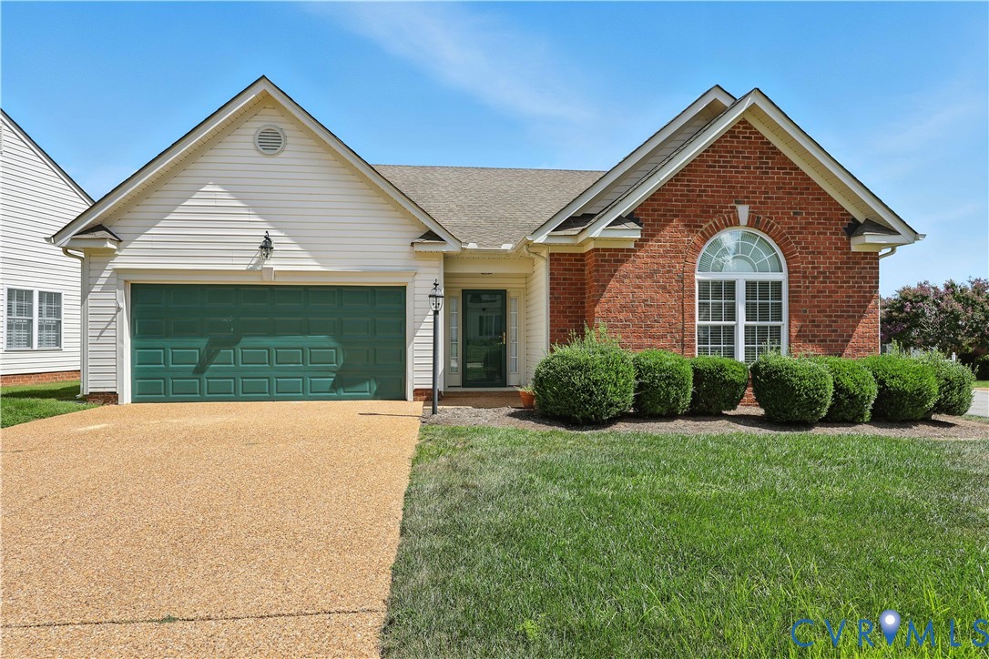 Single-story home with red brick, white siding, a green double garage door, and an arched front window.