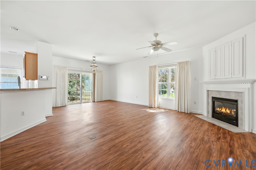 Vacant living room with wood-look floors, a white fireplace, and sliding glass doors.