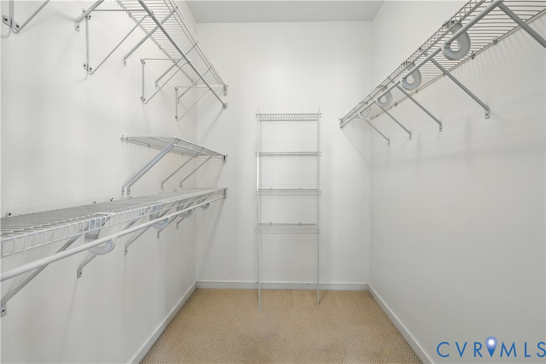 Walk-in closet with wire shelving on three walls and beige carpet.