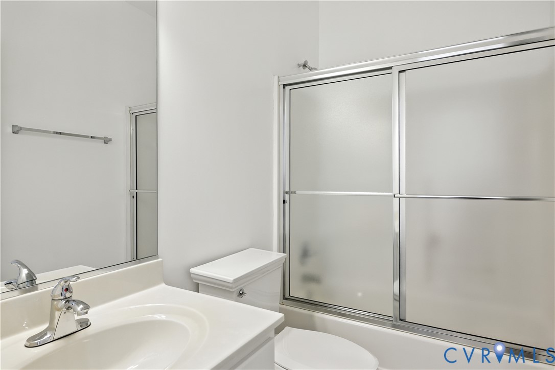 Bathroom with a white vanity, toilet, and frosted-glass sliding shower doors.