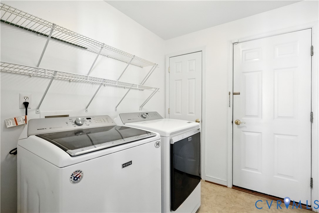 Laundry room with a Maytag washer and matching dryer beneath long wire shelves.