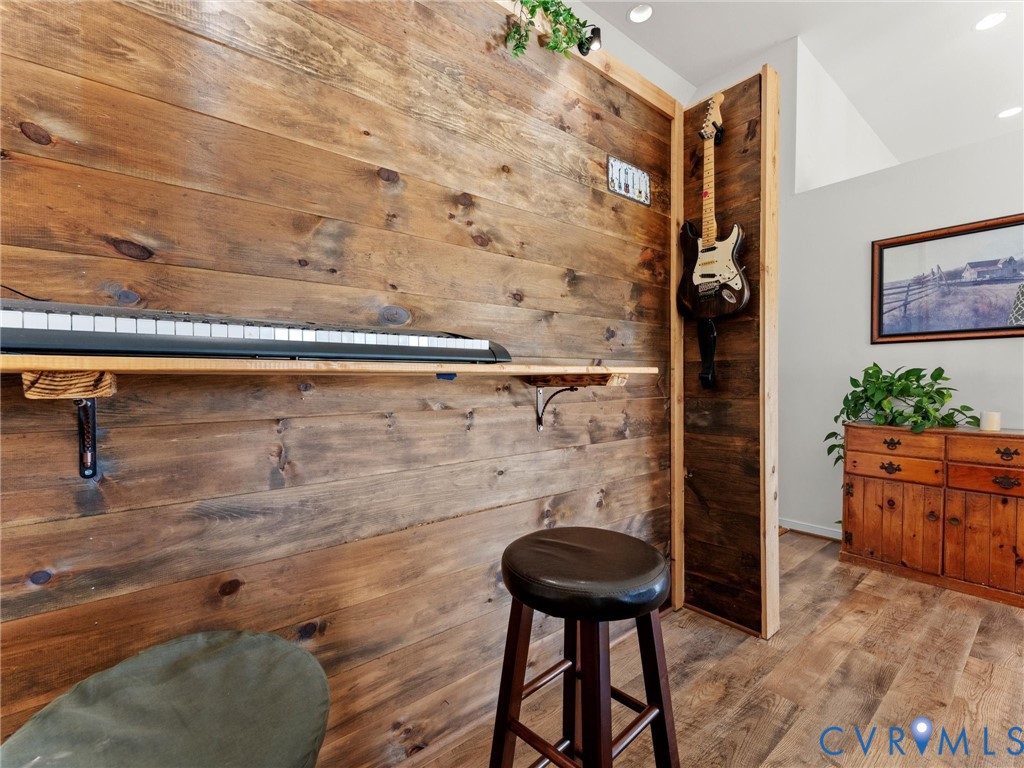 Music room with a rustic wood-plank wall, wall-mounted keyboard, and guitar in a wooden alcove.