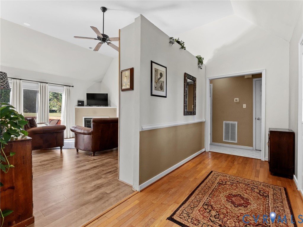 Entry hall with hardwood floors and patterned rug opening into a bright living room with leather seating.