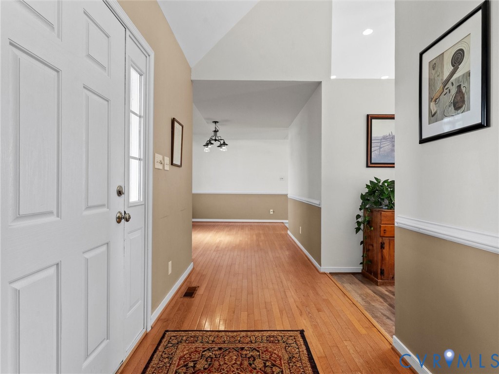 Entry hall with a white paneled front door, polished hardwood floors, and a patterned rug.