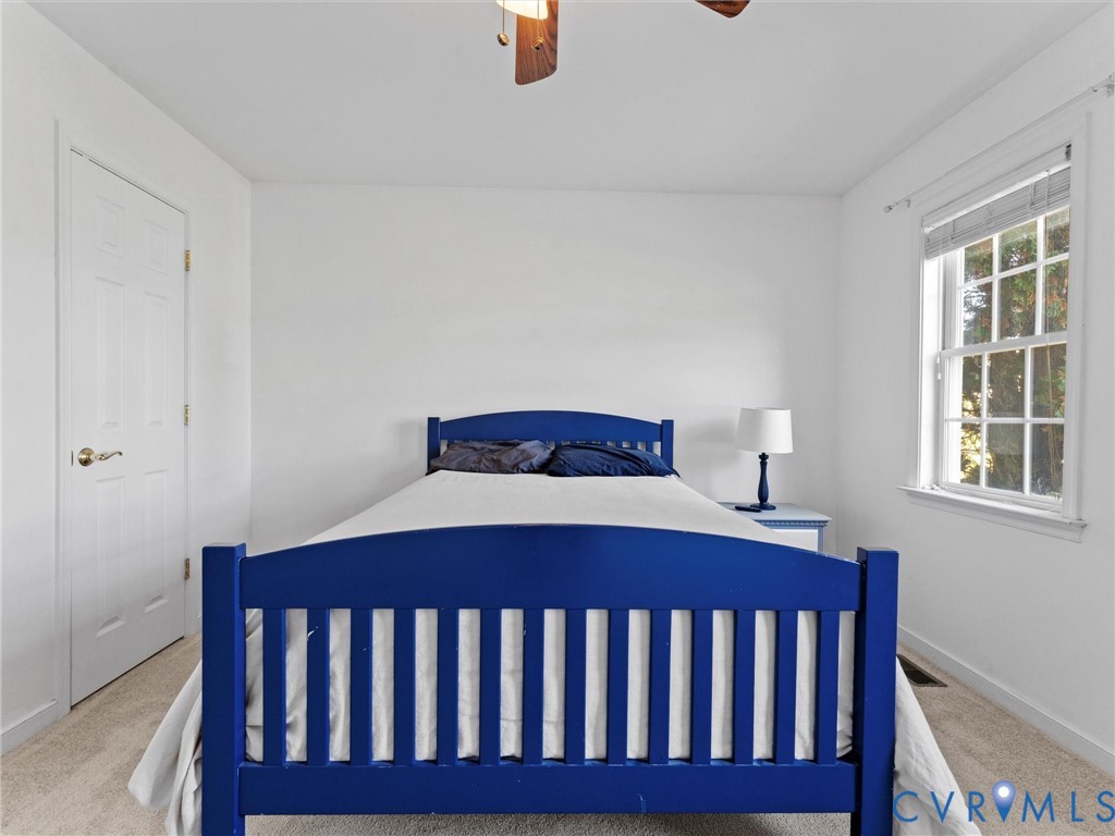 Bedroom with a vivid blue bed frame, beige carpet, and a window with blinds.