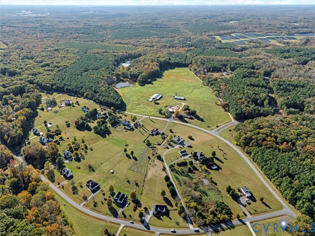 Aerial view of rural acreage with open fields, scattered homes, and surrounding autumn woodland.