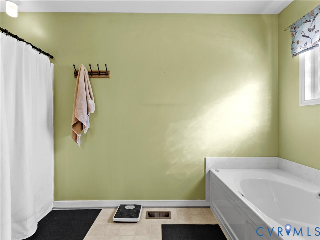 Bathroom with a white bathtub, shower curtain, and pale green walls.