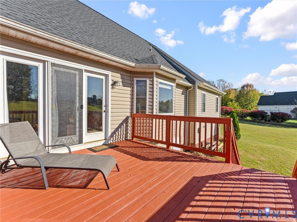 Rear deck with red-stained boards and railing, lounge chairs, and sliding glass doors.