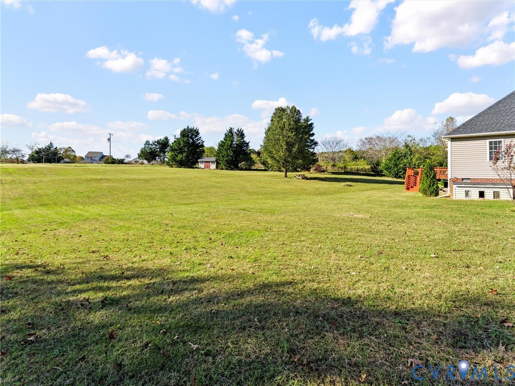 Expansive backyard lawn with mature trees, a small shed, and part of the house and deck.