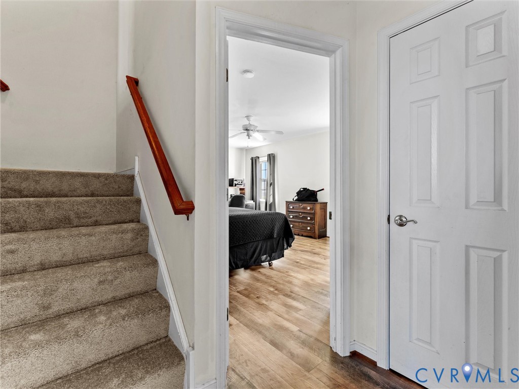 Carpeted stairs and hallway open onto a bedroom with wood-look flooring.
