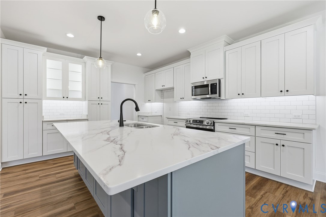 Kitchen with white cabinets, a large veined-stone island, and stainless steel appliances.