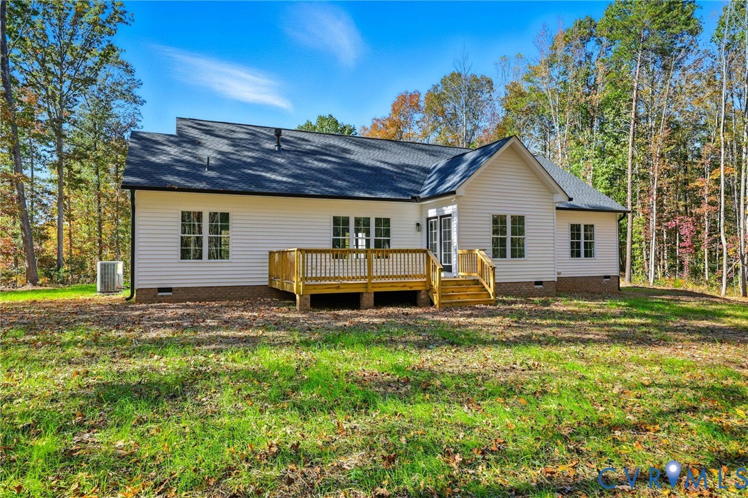 House rear exterior with a raised wooden deck and steps, surrounded by autumn trees.