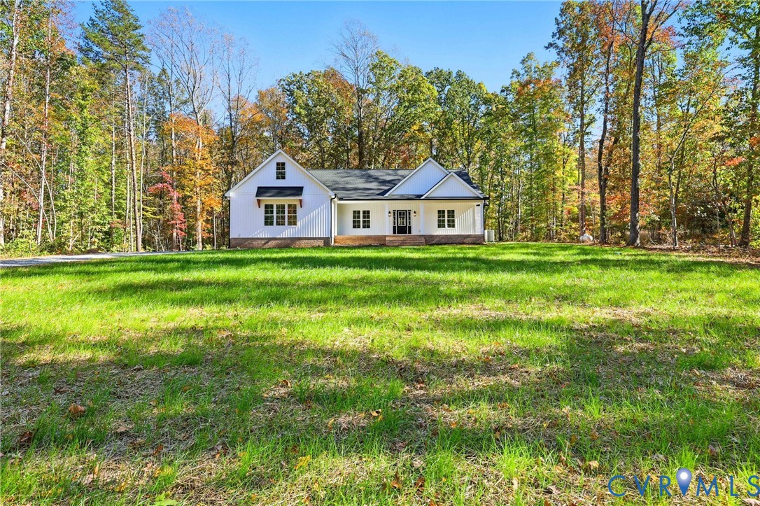 White single-story home with a broad green lawn and autumn trees.