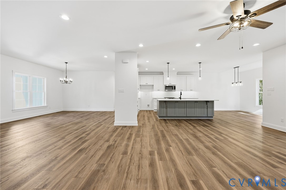Open-plan kitchen and living area with a gray island and wood-look flooring.