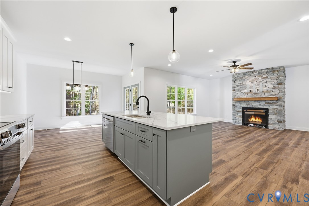 Open-concept kitchen with a large gray island and a stone fireplace in the adjoining living area.