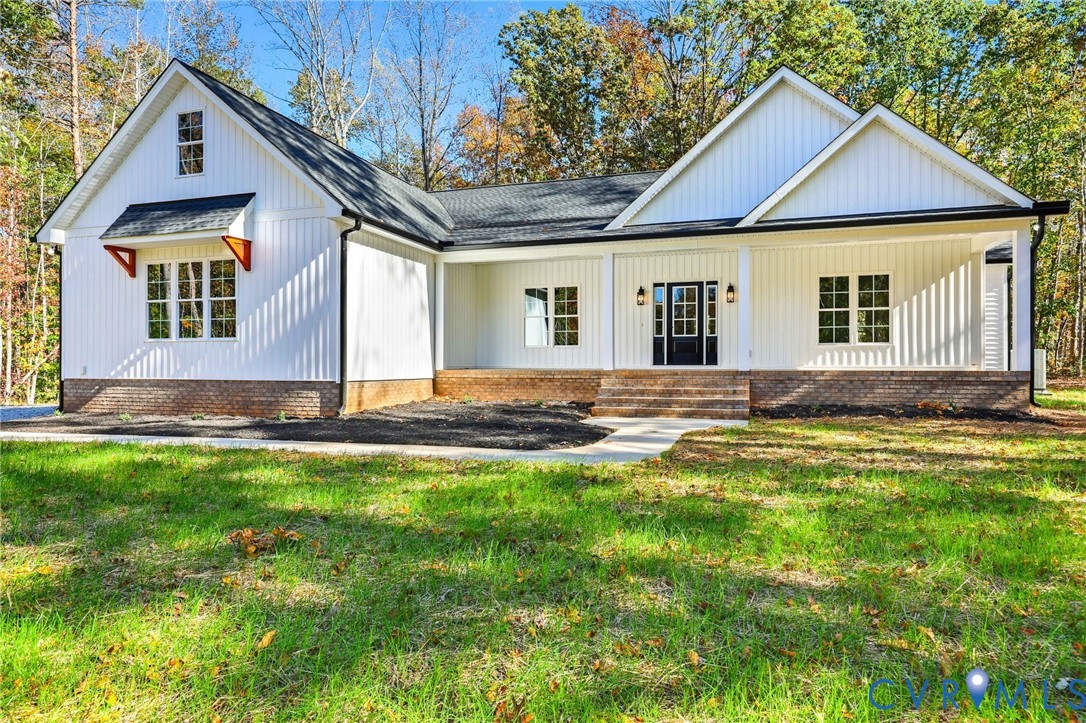 White single-story home with multiple gables, a brick foundation, and a covered front entry.