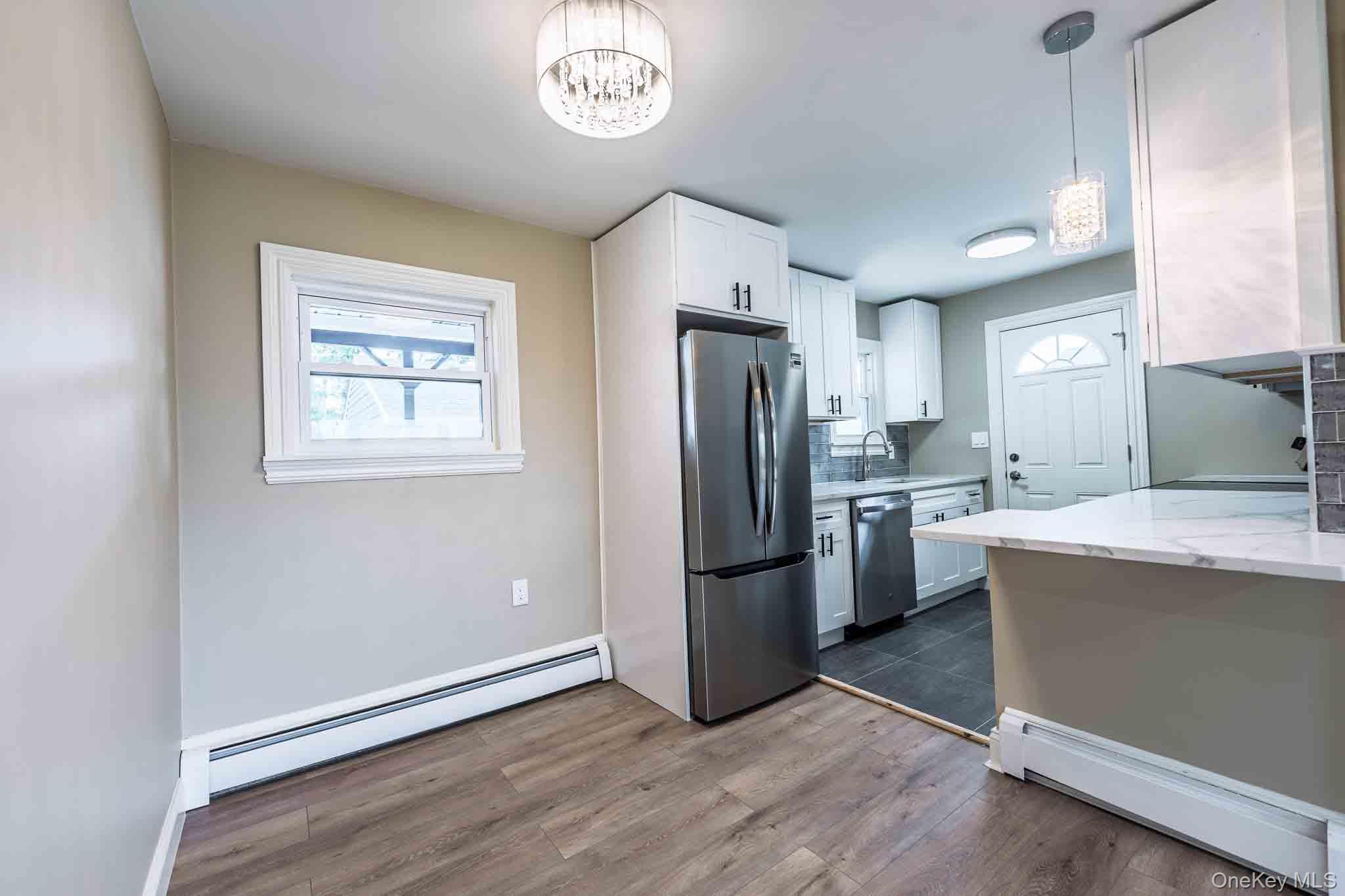 Kitchen with white cabinets, stainless steel appliances, and a white island.