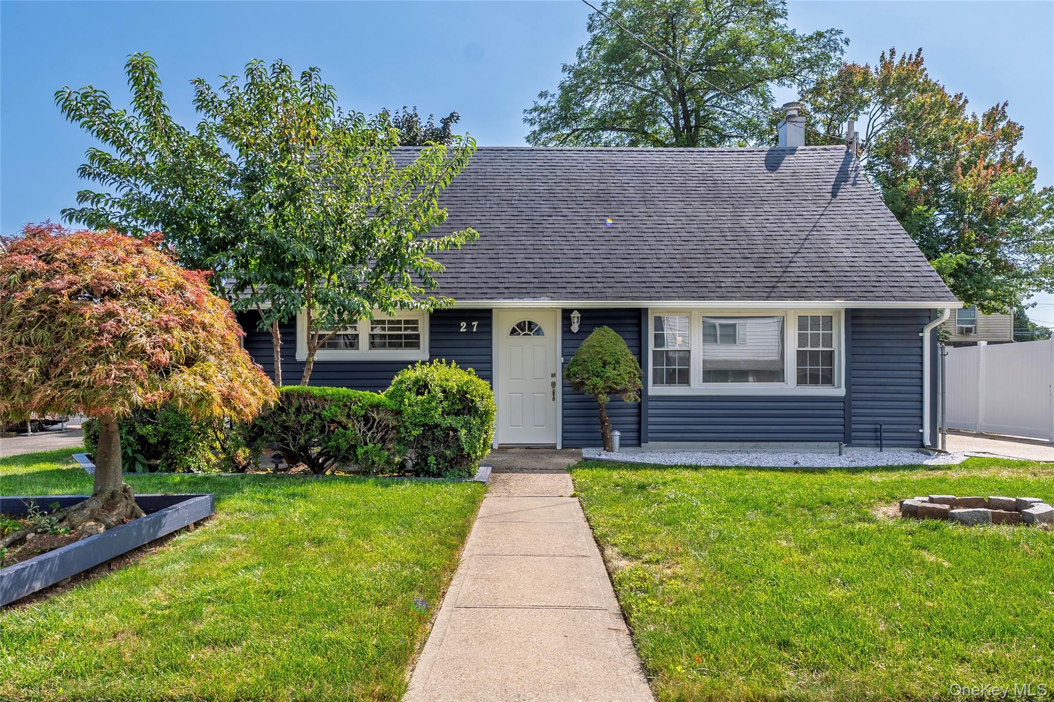 Blue-sided home with white trim, landscaped front yard, and concrete walkway.