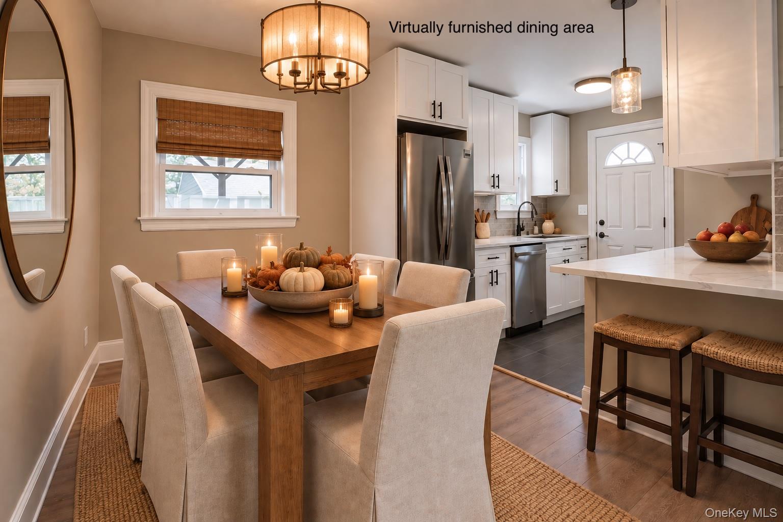 Dining area with a wood table and upholstered chairs beside a bright white kitchen and marble island.