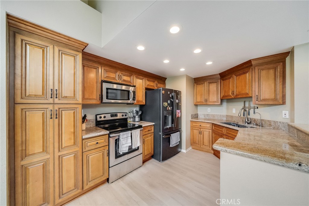 Kitchen with warm wood cabinets, granite counters, stainless steel range, and a peninsula sink.