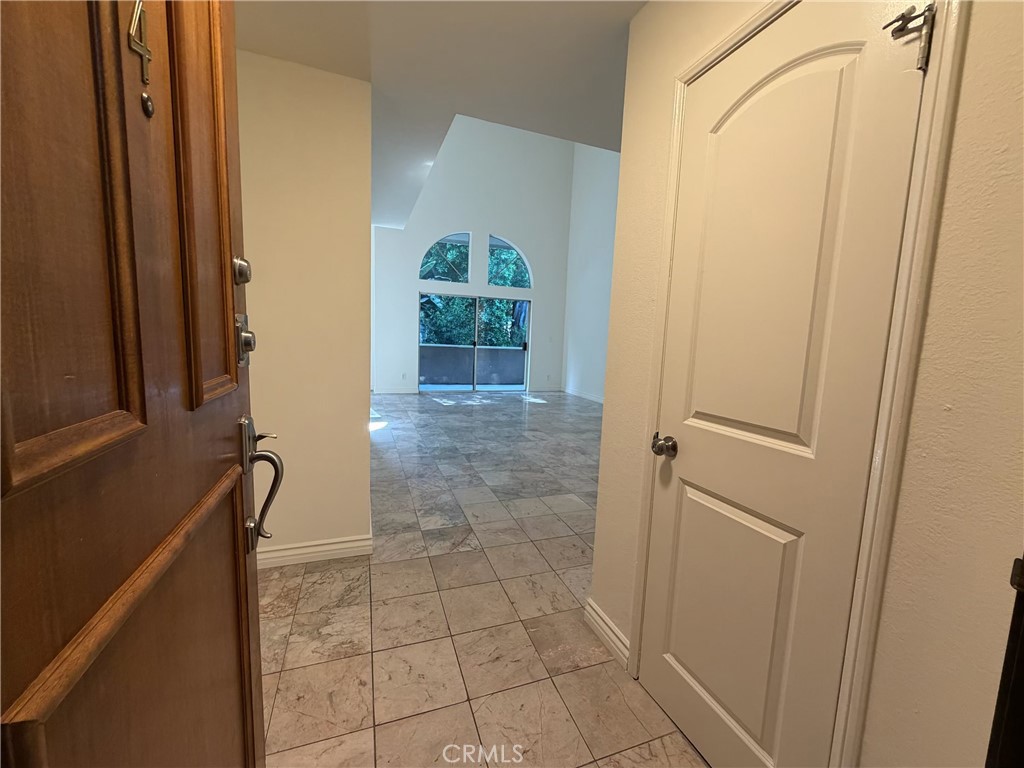 Tiled entry opens to a vacant living area with an arched window above glass doors.
