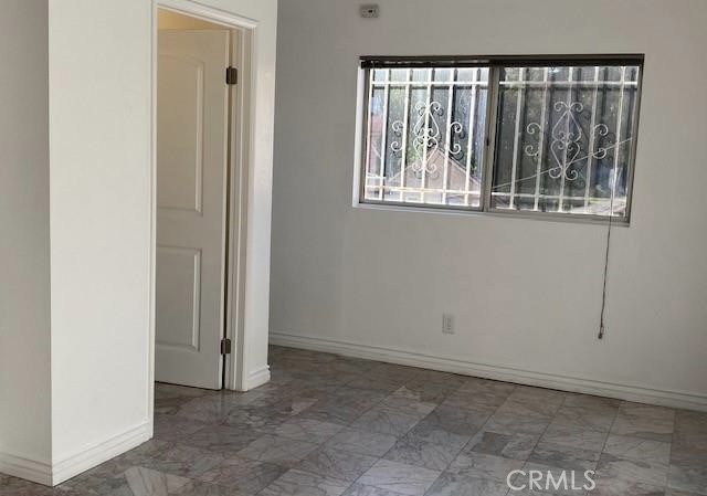Empty room with gray patterned tile flooring and a wide barred window.