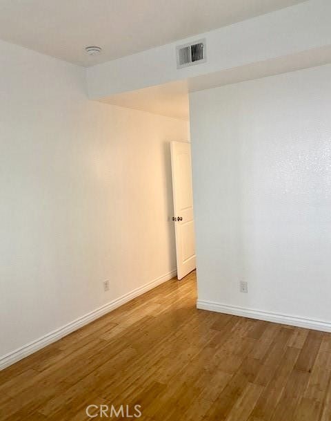 Vacant interior with warm-toned hardwood flooring and an open doorway.