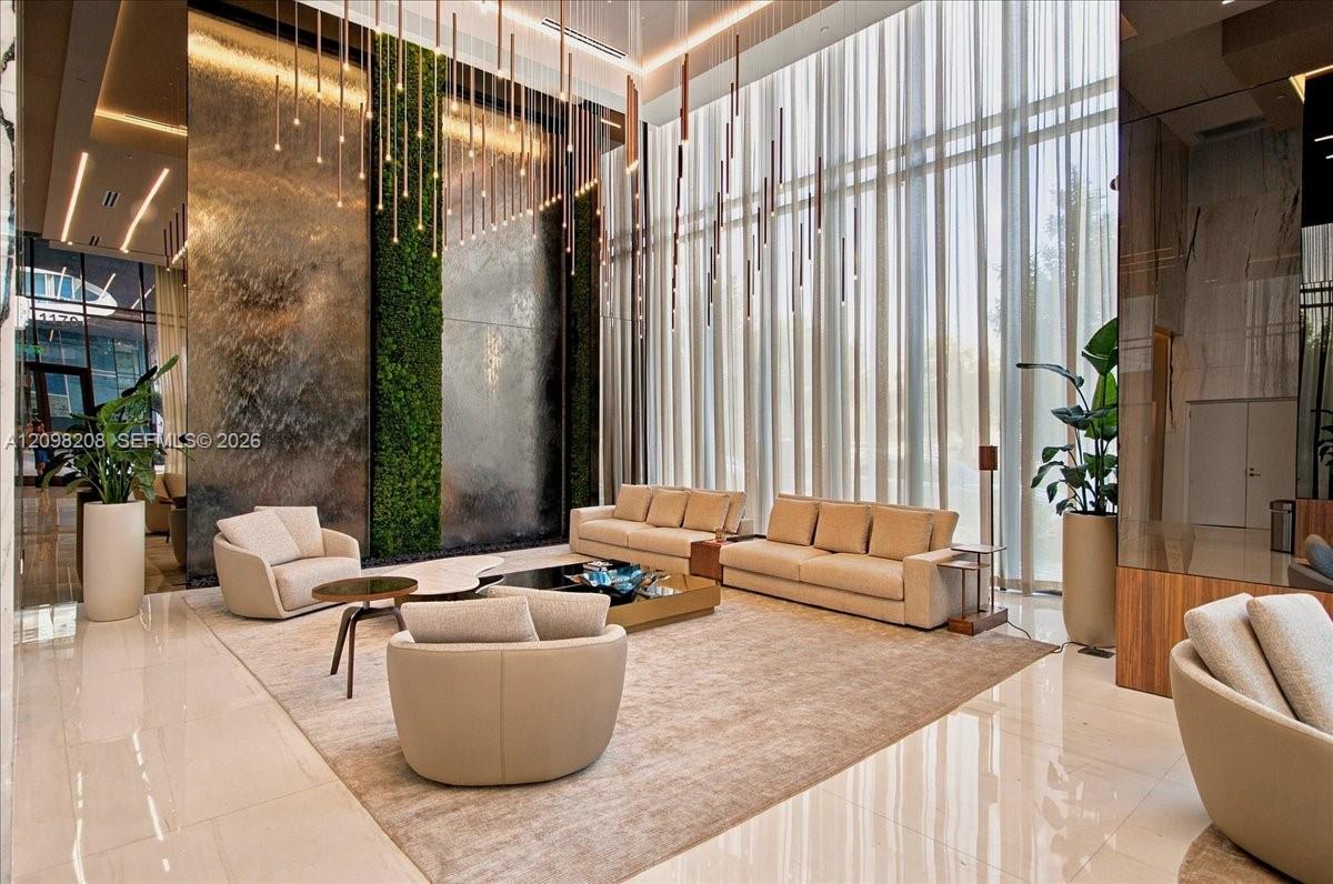 High-rise lobby with cream seating, a green living wall, and tall curtained windows.
