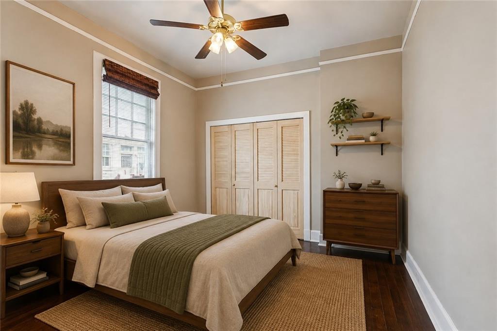 Bedroom with cream bedding, an olive-green throw, and louvered closet doors.