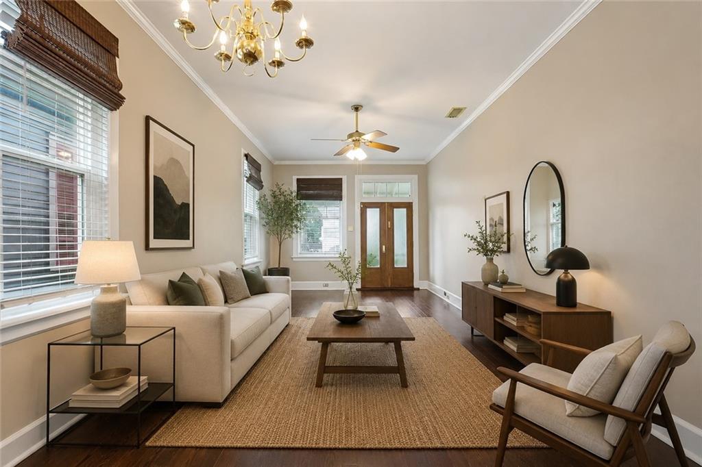 Furnished living room with a cream sofa, woven rug, oval mirror, and wooden double door.