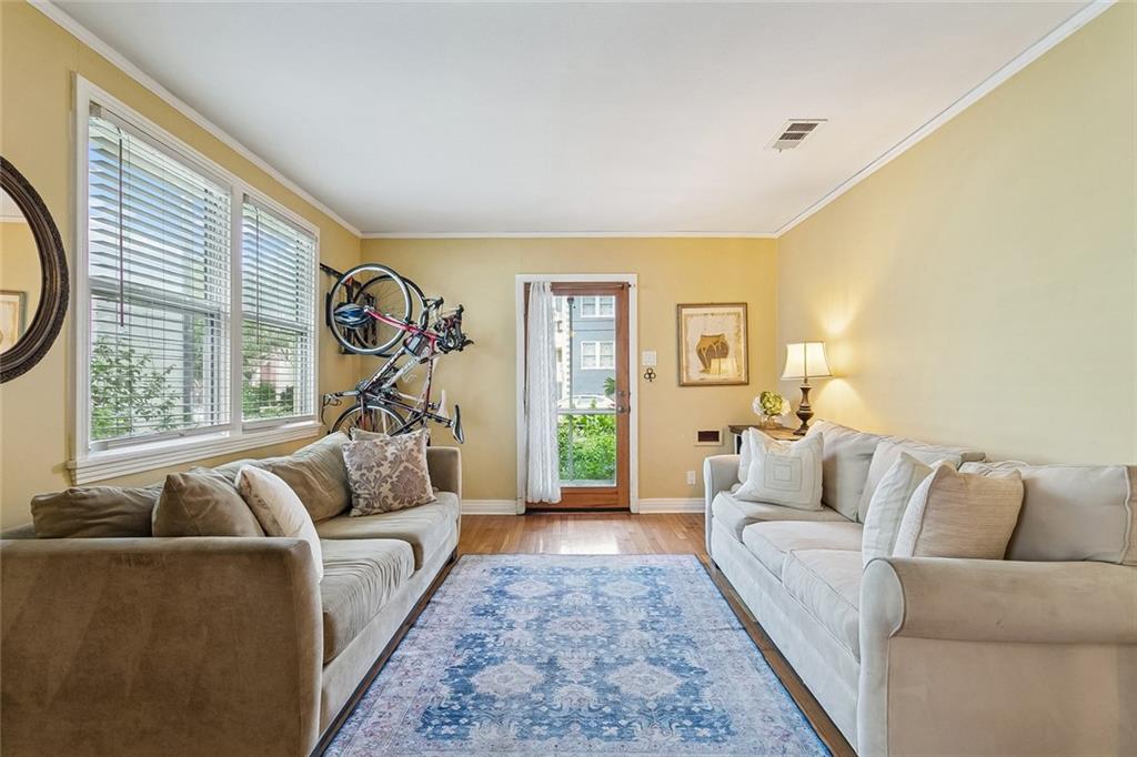 Living room with two sofas, a blue patterned rug, and bicycles mounted above the sofa.