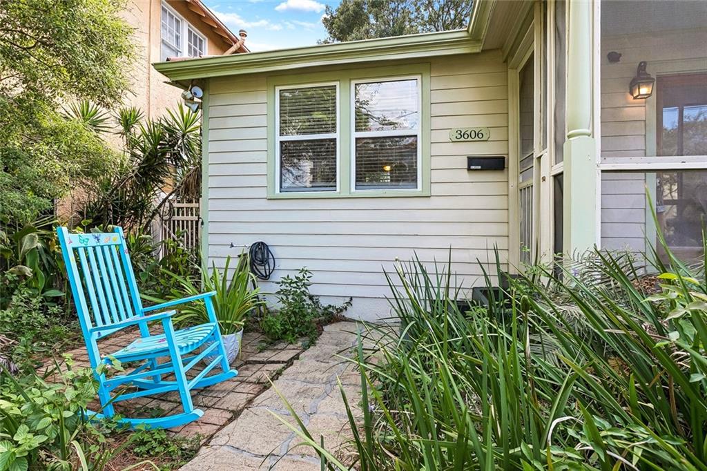 House entry with pale siding, a stone garden path, and a bright blue rocking chair.