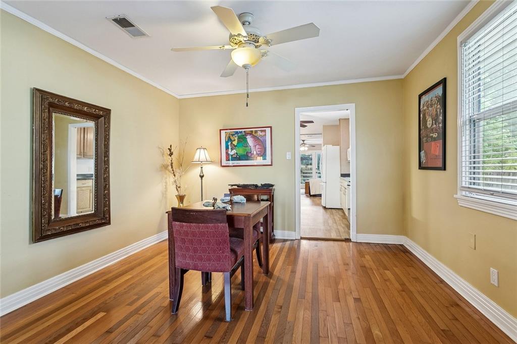 Dining room with hardwood floors, a dark wood table, burgundy chairs, and an open doorway to the kitchen.