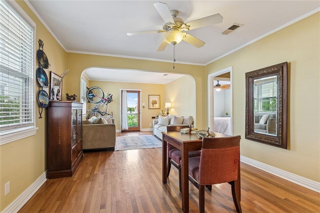 Living and dining area with hardwood floors, a ceiling fan, and an arched opening to the sitting room.