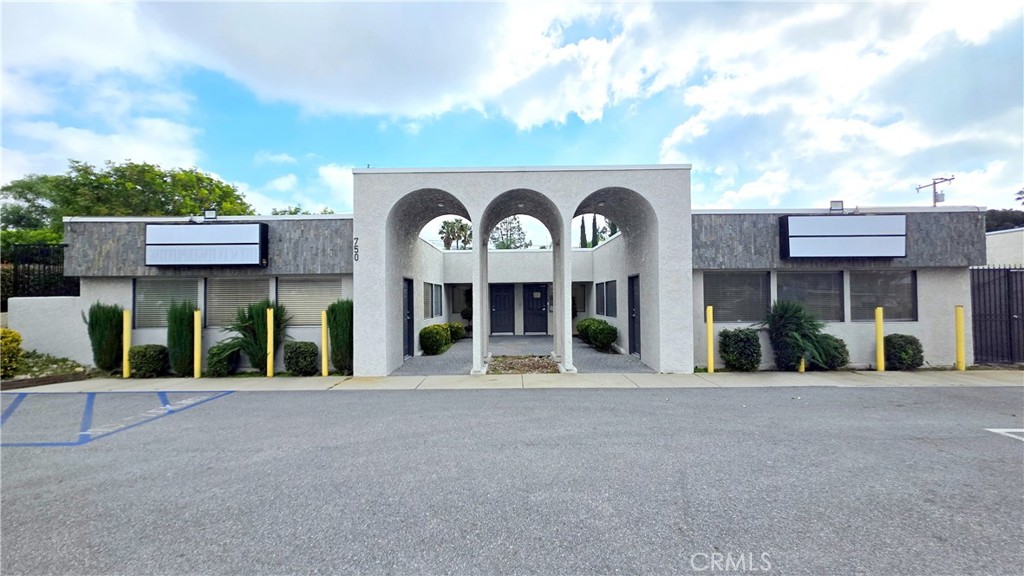Commercial building with a central entrance framed by three arches and storefront windows.