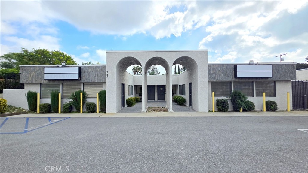 Commercial building with a central entrance framed by three large arches and parking spaces in front.