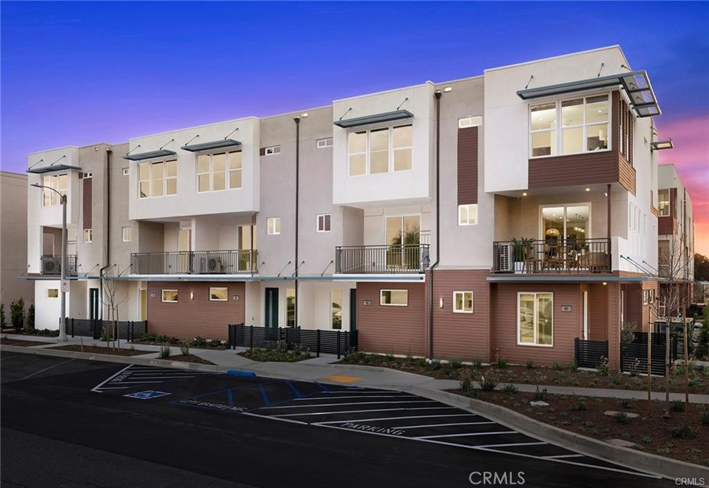 Modern attached homes with balconies and large windows at dusk.