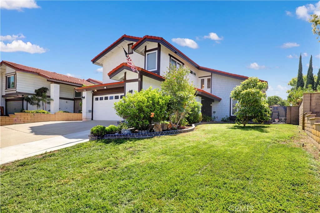 Two-story white house with red tile roof accents, a garage, and a landscaped lawn.