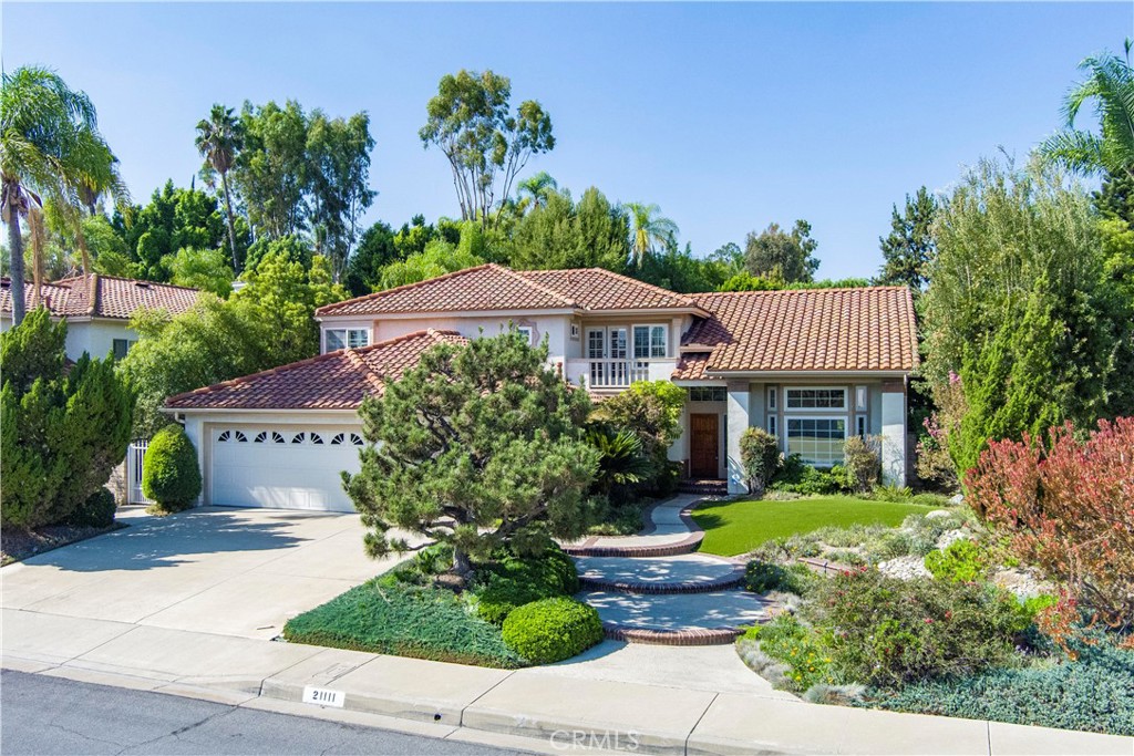Two-story home with a tiled roof, attached garage, and landscaped front garden.