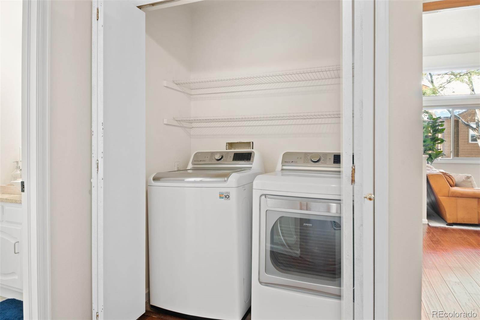 Laundry closet with a top-loading washer, front-loading dryer, and two wire shelves.