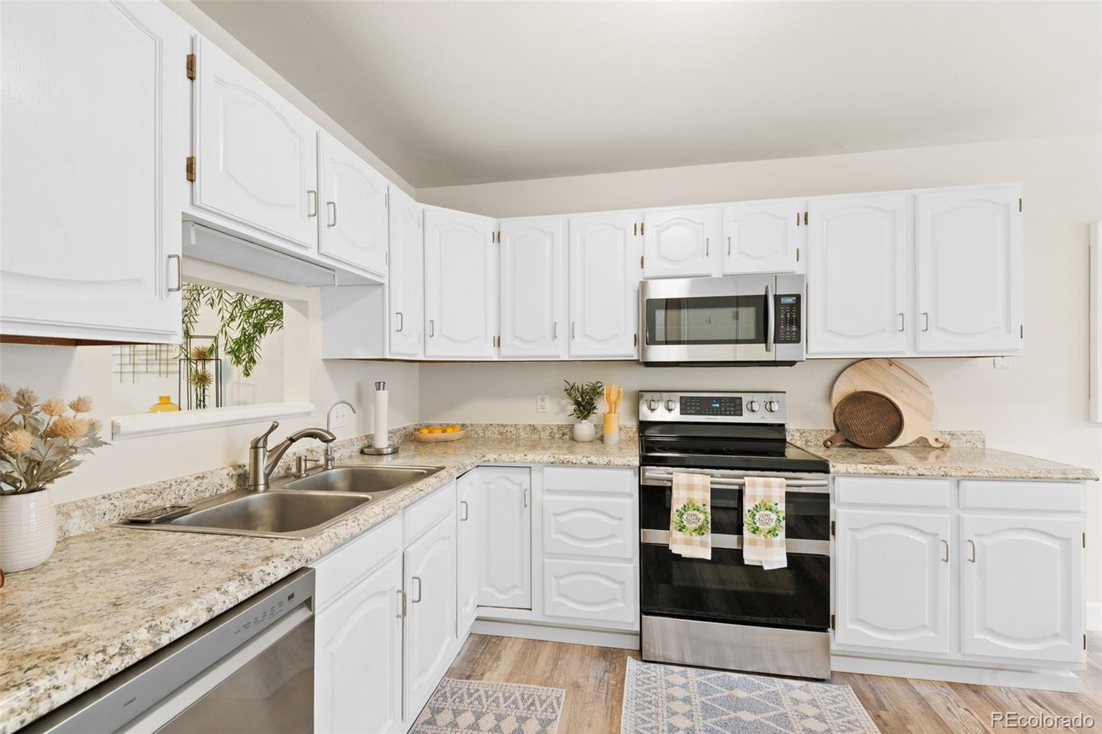 Kitchen with white cabinetry, granite counters, and stainless-steel appliances.