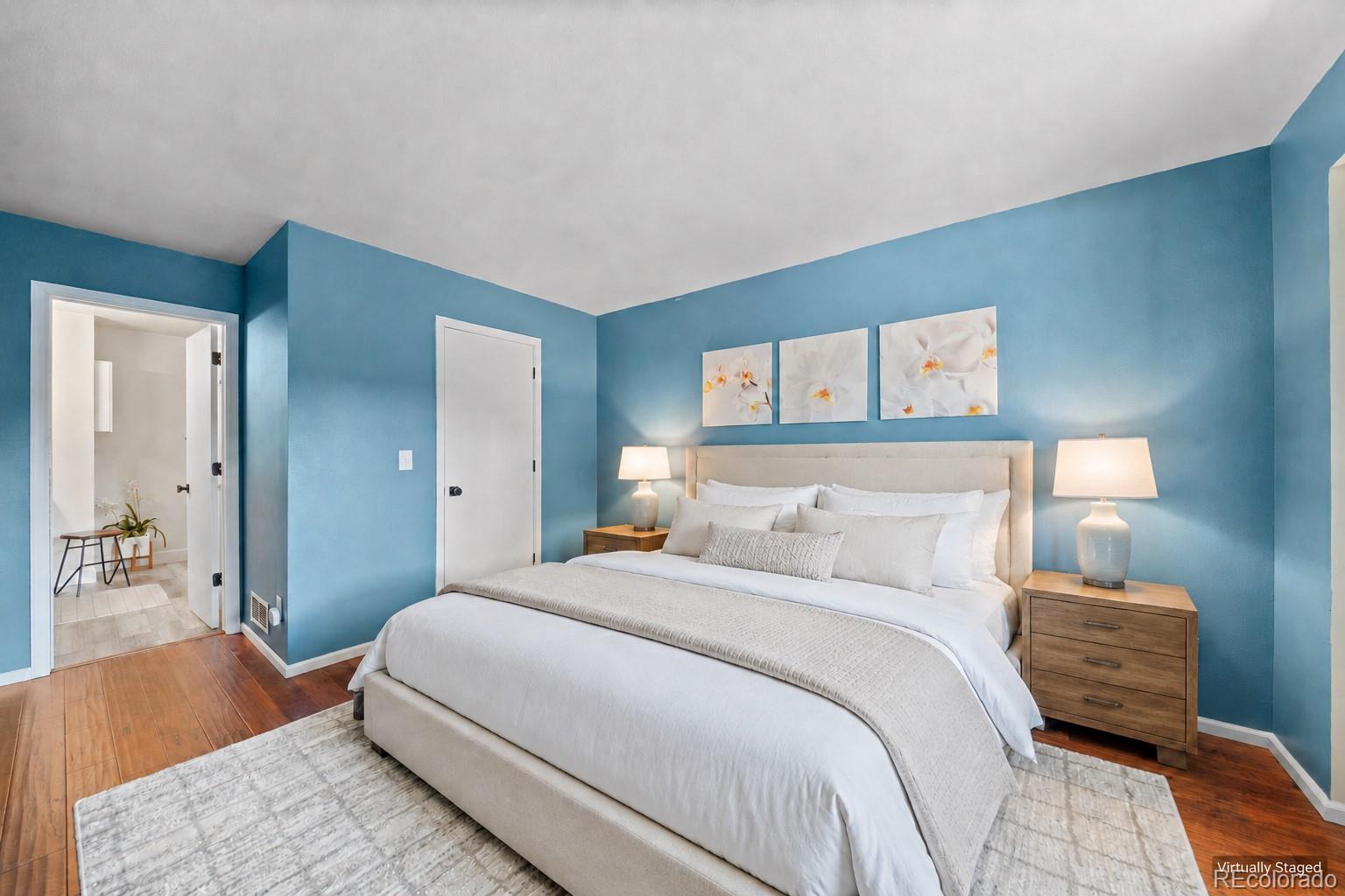 Staged bedroom with a white bed against blue walls and matching wooden nightstands.